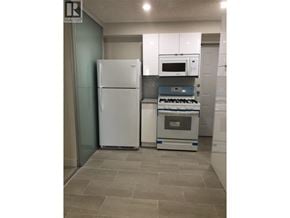 West Vancouver apartment for rent - A bedroom with a black couch and a bed with a black and white comforter.
