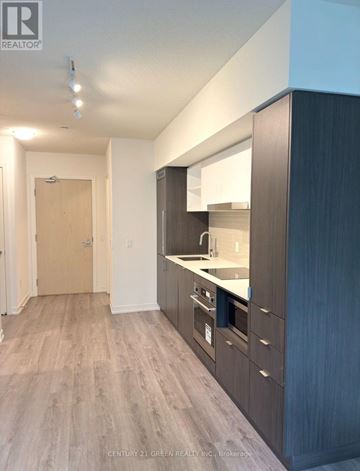 Toronto (Waterfront Communities) condo for rent - A kitchen with wooden cabinets and a white countertop.