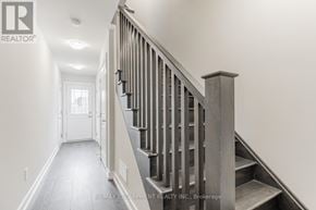 Hamilton (Stoney Creek Mountain) townhouse for rent - A staircase with a wooden handrail and steps leading up to a door at the end of the hallway.