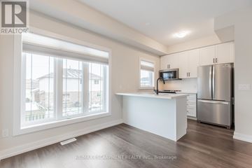 Hamilton (Stoney Creek Mountain) townhouse for rent - A spacious kitchen with white cabinets and a stainless steel refrigerator.