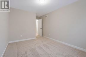 Ottawa townhouse for rent - A spacious room with beige carpeting and white walls.
