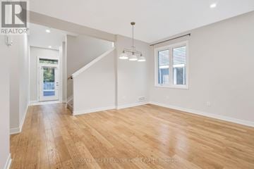 Ottawa townhouse for rent - A spacious room with wooden flooring and white walls.