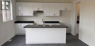 Wasaga Beach apartment for rent - A kitchen with white cabinets and a black countertop.