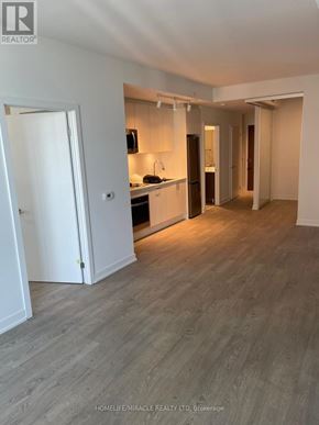 Toronto (High Park-Swansea) condo for rent - A spacious room with a kitchen area and a door leading to another room.