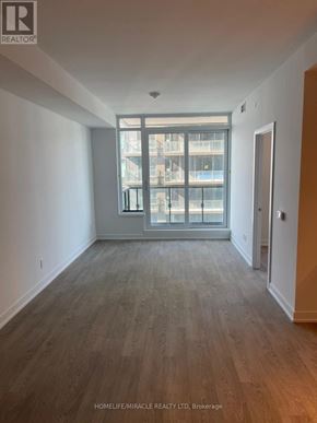 Toronto (High Park-Swansea) condo for rent - A room with wooden flooring and a large window overlooking a balcony.