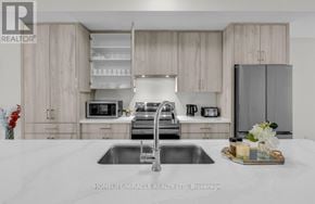 Oakville (Oa Rural Oakville) townhouse for rent - A modern kitchen with a sink, microwave, and refrigerator.