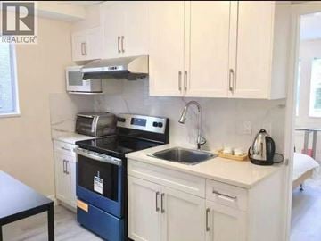 Vancouver apartment for rent - A kitchen with white cabinets and a blue oven.