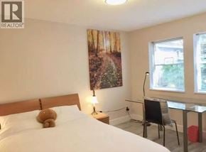 Vancouver apartment for rent - A bedroom with a large bed, a chair, and a painting on the wall.