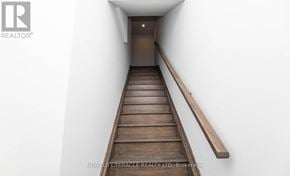 Toronto (New Toronto) townhouse for rent - A wooden staircase with a white wall on one side and a wooden handrail on the other.