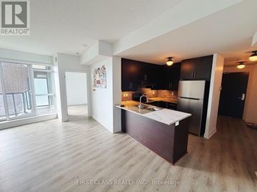 Markham (Unionville) condo for rent - A kitchen with dark brown cabinets and a white fridge is shown.