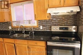 Toronto (L'amoreaux) apartment for rent - A kitchen with wooden cabinets and a black countertop.