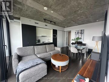 Toronto (Moss Park) condo for rent - A living room with a grey couch and a wooden coffee table.