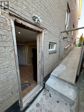 Brampton (Fletcher's Meadow) apartment for rent - A view of a doorway leading to a room with a brick wall on the left and a concrete staircase on the right.
