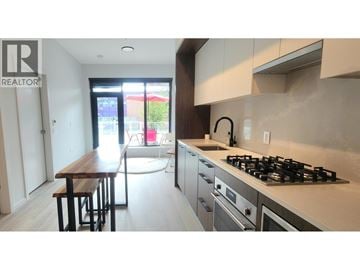 Vancouver townhouse for rent - A modern kitchen with a wooden table and stainless steel appliances.