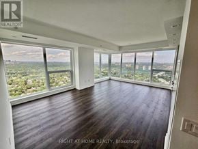 Toronto (North St. James Town) house for rent - A spacious room with wooden floors and large windows overlooking a cityscape.