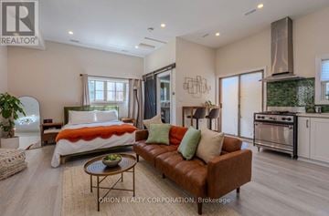 Burlington (Mountainside) apartment for rent - A well-lit, modern living room with a brown leather sofa and a bed with an orange blanket.