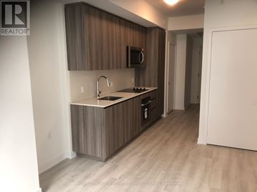 Toronto (Waterfront Communities) condo for rent - A kitchen with wooden cabinets and a microwave above the stove.