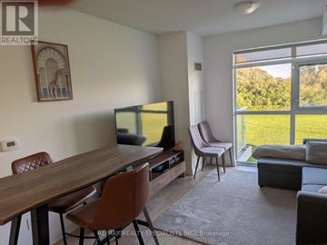 Toronto (Mimico) condo for rent - A living room with a wooden table and chairs, a television, and a large window with a view of the outdoors.
