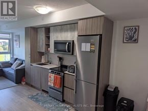 Toronto (Mimico) condo for rent - A kitchen area with a refrigerator, microwave, oven, and a couch.