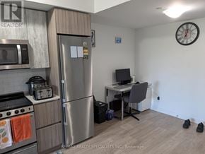Toronto (Mimico) condo for rent - A kitchen with a refrigerator, microwave, toaster, and a small desk with a computer.