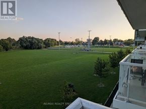 Toronto (Mimico) condo for rent - A view from a balcony overlooking a green field with trees and a stadium in the distance.