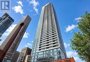 Toronto (North St. James Town) condo for rent - A tall building with many windows stands in front of other buildings.