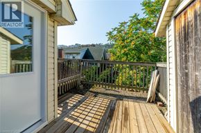 Hamilton apartment for rent - A wooden deck with a railing and a view of a house and trees.