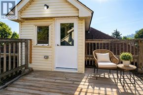 Hamilton apartment for rent - A small house with a white door and a wooden deck with a chair and a potted plant.