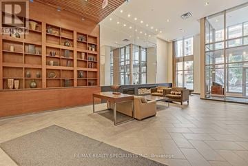 Mississauga (City Centre) condo for rent - A spacious living room with a wooden bookshelf and a large window.