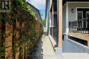 Toronto (Blake-Jones) apartment for rent - A narrow alley with a wooden fence covered in greenery and a sign that says REALTOR.
