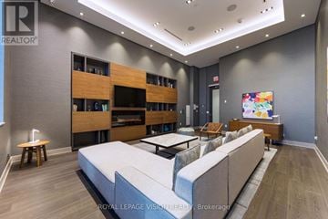 Toronto (Waterfront Communities) condo for rent - A modern living room with a grey sofa and wooden shelves.