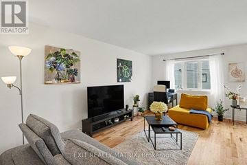 Clarence-Rockland townhouse for rent - A living room with a grey couch, a yellow chair, a black television, and a painting of flowers on the wall.