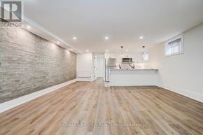 Toronto (The Beaches) multi-family for rent - A spacious room with wooden flooring and a brick wall.