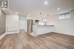 Toronto (The Beaches) multi-family for rent - A spacious kitchen with wooden flooring and white walls.
