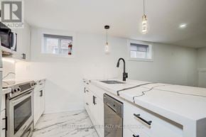 Toronto (The Beaches) multi-family for rent - A white kitchen with a sink and a window.