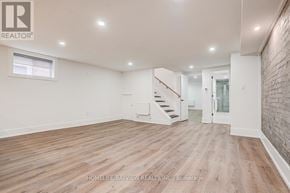 Toronto (The Beaches) multi-family for rent - A spacious room with wooden flooring and a staircase leading to another room.