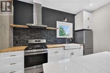 Hamilton apartment for rent - A modern kitchen with a black wall and a stove top oven.