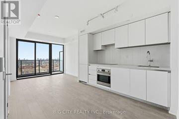 Toronto (Thorncliffe Park) condo for rent - A modern kitchen with white cabinets and a view of the city.