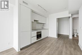 Toronto (Thorncliffe Park) condo for rent - A white kitchen with wood floors and a white wall.