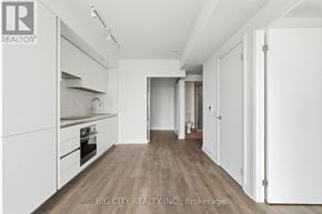 Toronto (Thorncliffe Park) condo for rent - A spacious kitchen with white cabinets and a wooden floor.