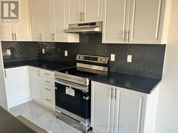 Thorold (Rolling Meadows) townhouse for rent - A kitchen with white cabinets and a black countertop.