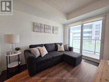 Toronto (Islington-City Centre West) condo for rent - A living room with a black couch and a lamp on a side table.