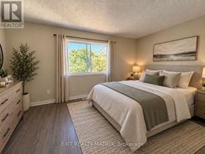 Ottawa townhouse for rent - A bedroom with a large bed, a window with curtains, and a painting on the wall.