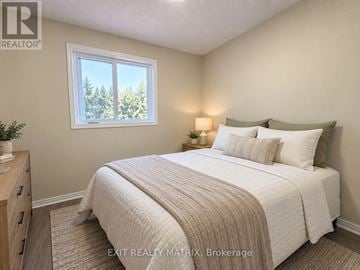 Ottawa townhouse for rent - A bedroom with a large bed and a window overlooking trees.