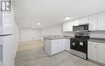 Pickering (Bay Ridges) apartment for rent - A kitchen with white cabinets and a black stove top oven.