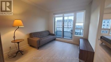 Markham (Unionville) condo for rent - A living room with a grey sofa and a table with a lamp on it.