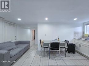 Burnaby apartment for rent - A grey couch sits in a white room with a dining table and chairs.