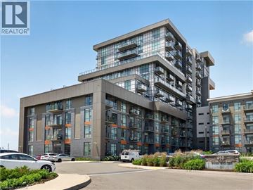 Waterdown condo for rent - A modern multi-story building with a parking lot in front.