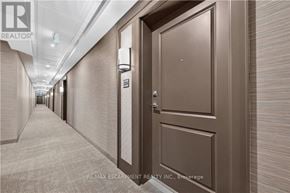 Hamilton (Waterdown) condo for rent - A hallway with a brown door and a sign that says RE/MAX Escarpment Realty Inc. Brokerage.