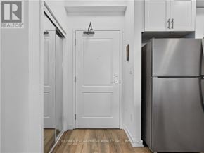 Hamilton (Waterdown) condo for rent - A white door in a hallway with a refrigerator on the right.